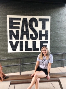 A woman sitting in front of a wall that says 