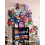 Hooks on a wall are filled with colorful purses and a bookshelf is lined with accessories.