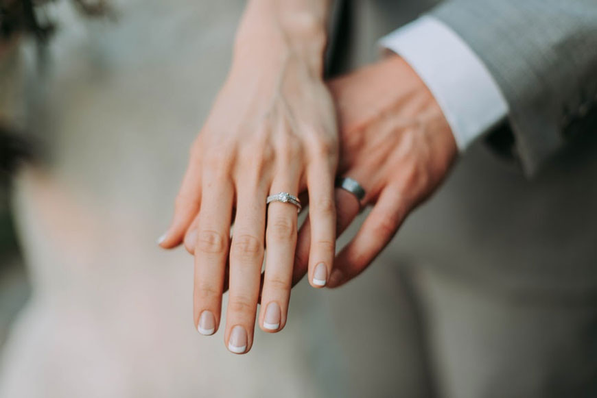 a bride and groom showing off their wedding bands